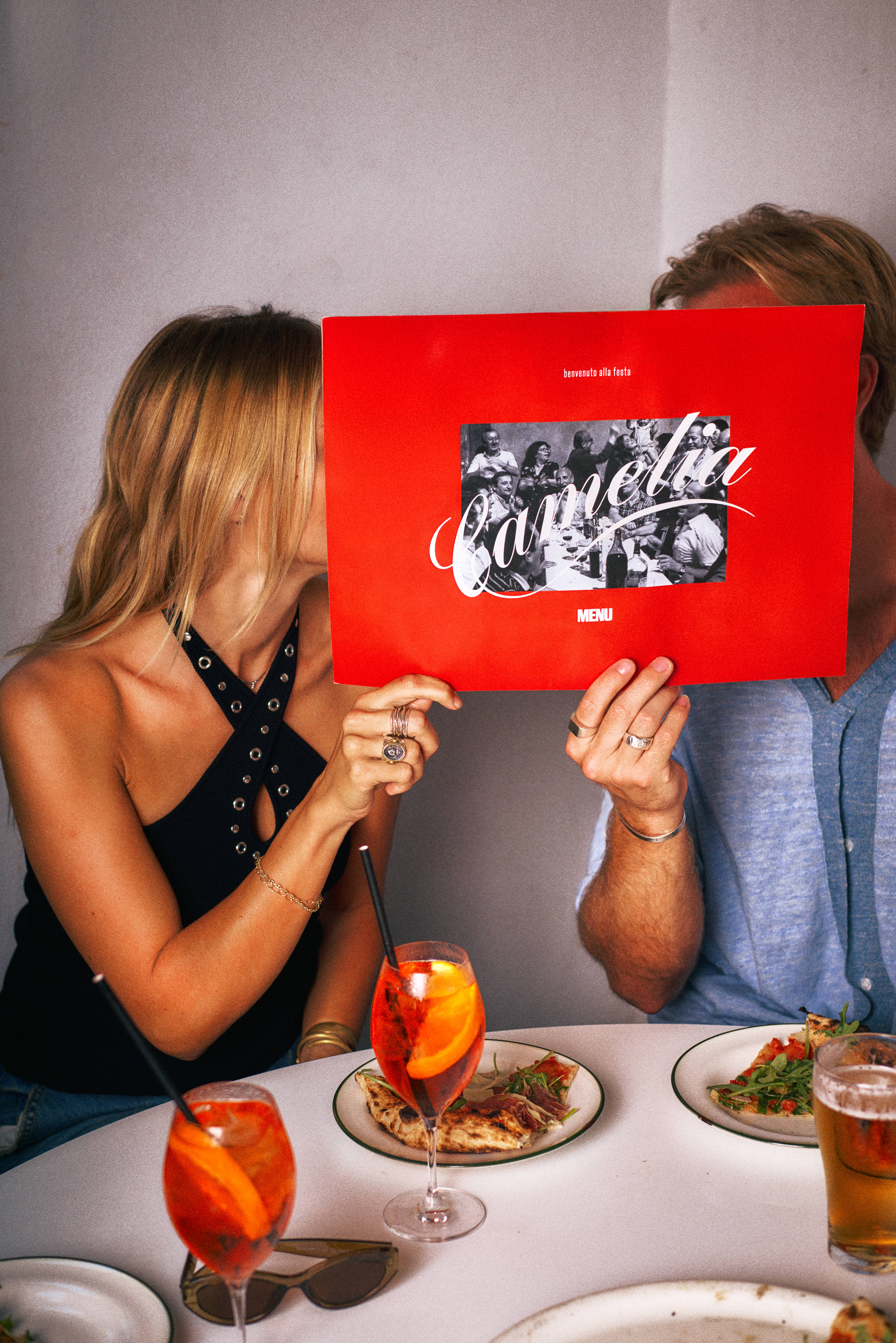 Couple hiding behind the red Ciao brunch menu