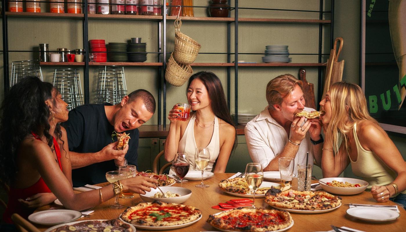 Friends sharing pizza and wine in the dining room