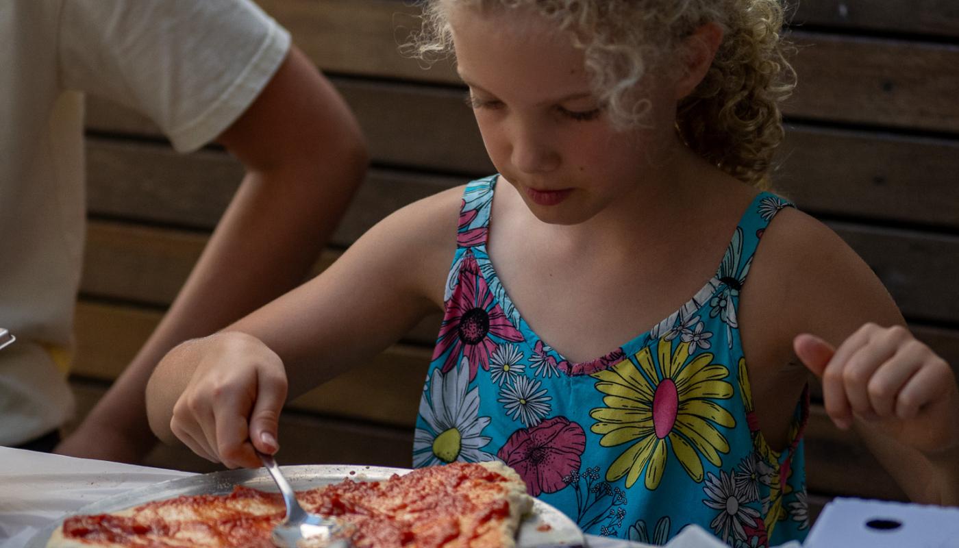 Young pizzaiolo spooning sauce at the pizza masterclass