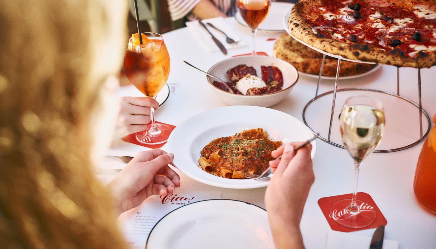 Pappardelle, spritz and pizza on a shared table