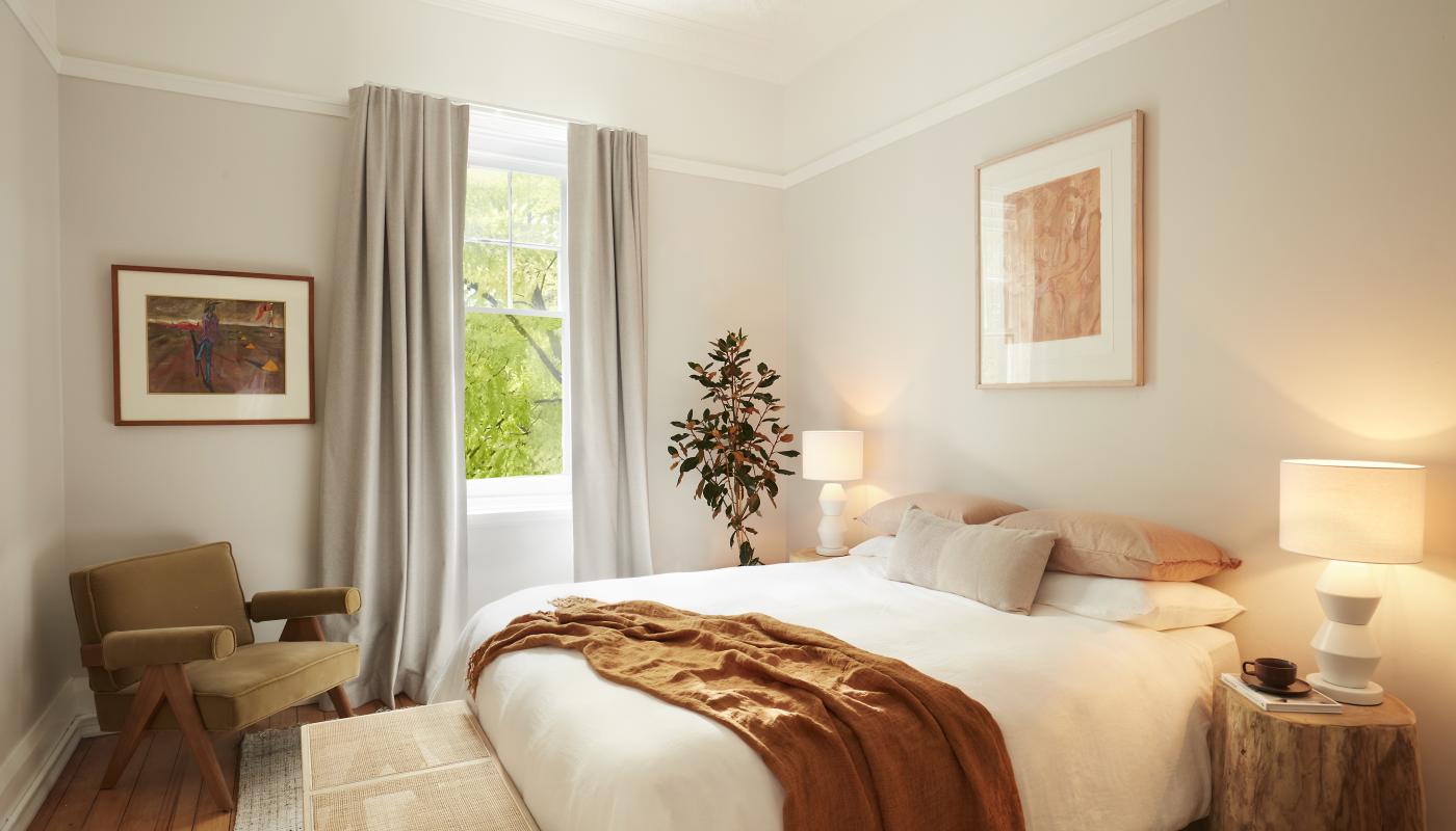 Heritage bedroom in warm linen tones with olive armchair